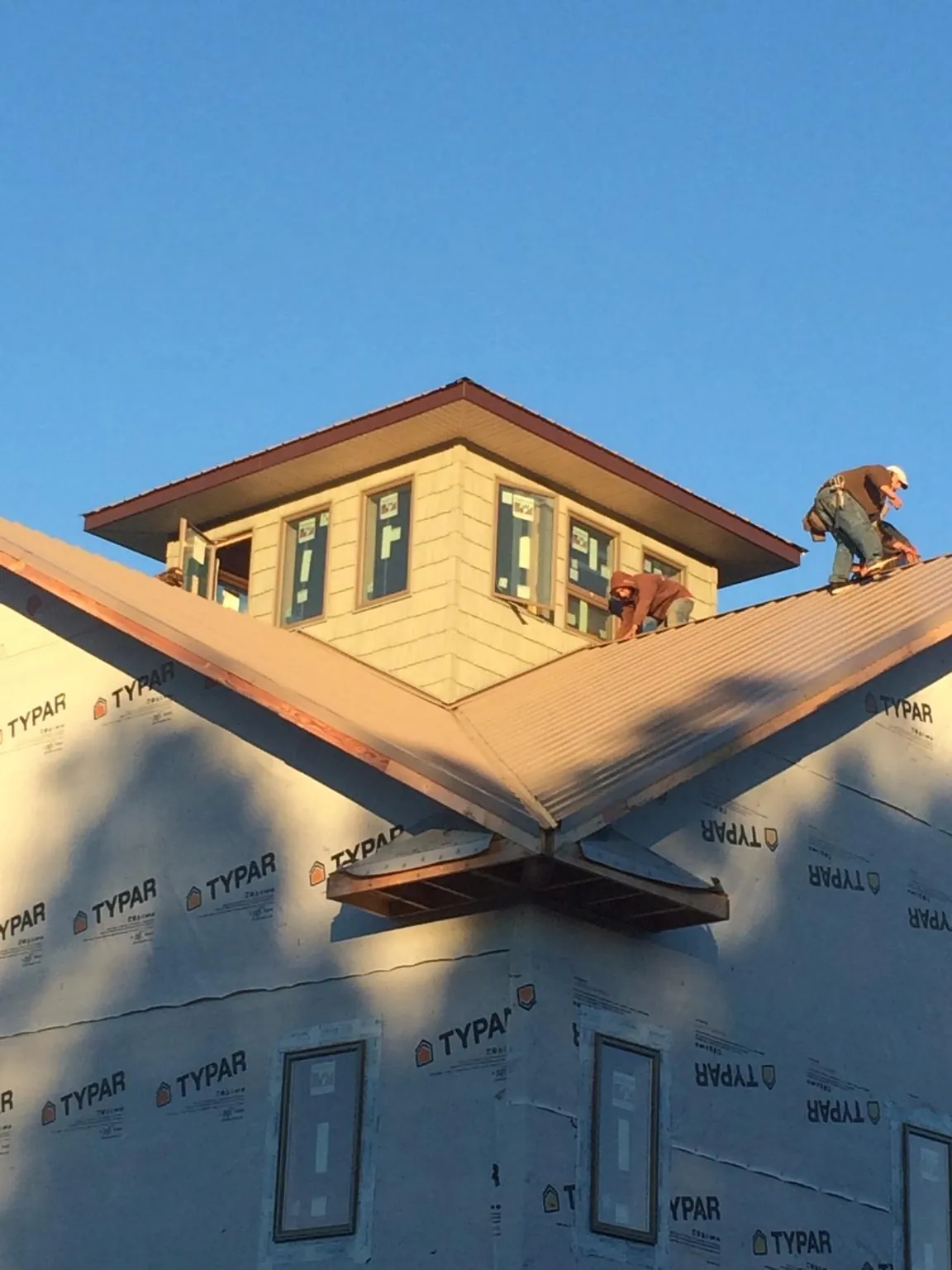 Roofers working around a rooftop cupola on a new metal roof at sunset — Roof Waterproofing in Benedict by Roofing Brothers